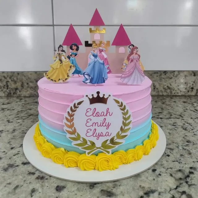 Bolo de aniversário em rosa, azul e amarelo, com castelo e princesas no topo